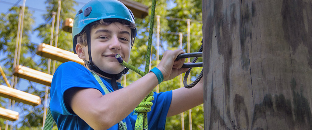happy male camper climbing challenge course